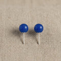 Pair of blue spherical earrings on a beige fabric background