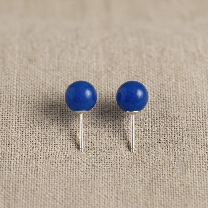 Pair of blue spherical earrings on a beige fabric background