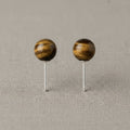 Pair of wooden ball earrings on a beige fabric background