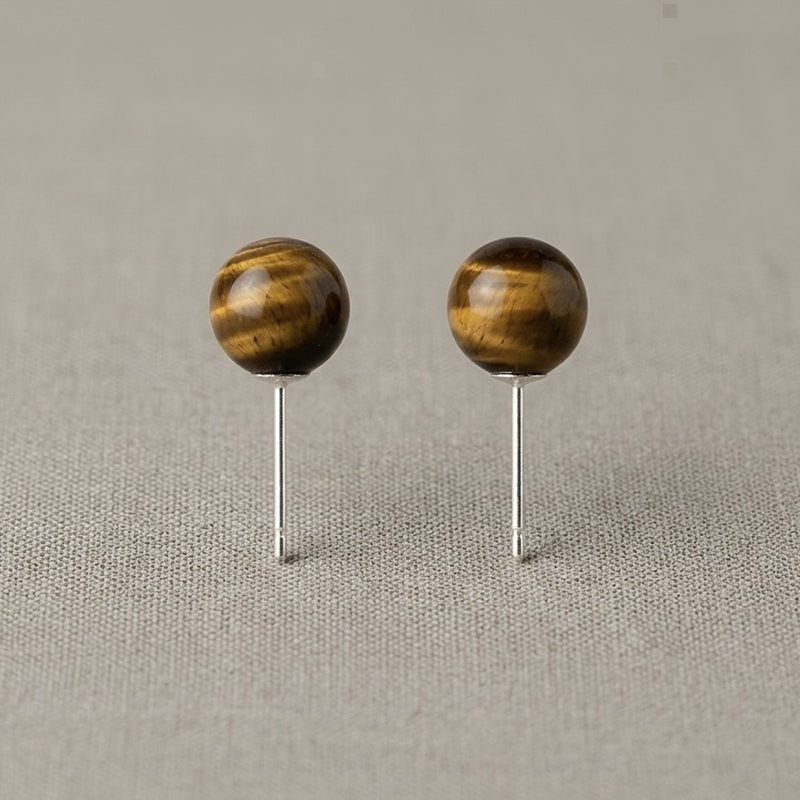 Pair of wooden ball earrings on a beige fabric background