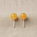 Two yellow spherical objects on metal stands against a beige fabric background