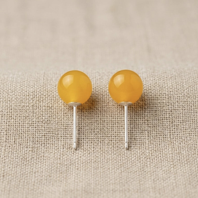 Two yellow spherical objects on metal stands against a beige fabric background