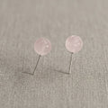 Pair of pink round earrings on a gray fabric background