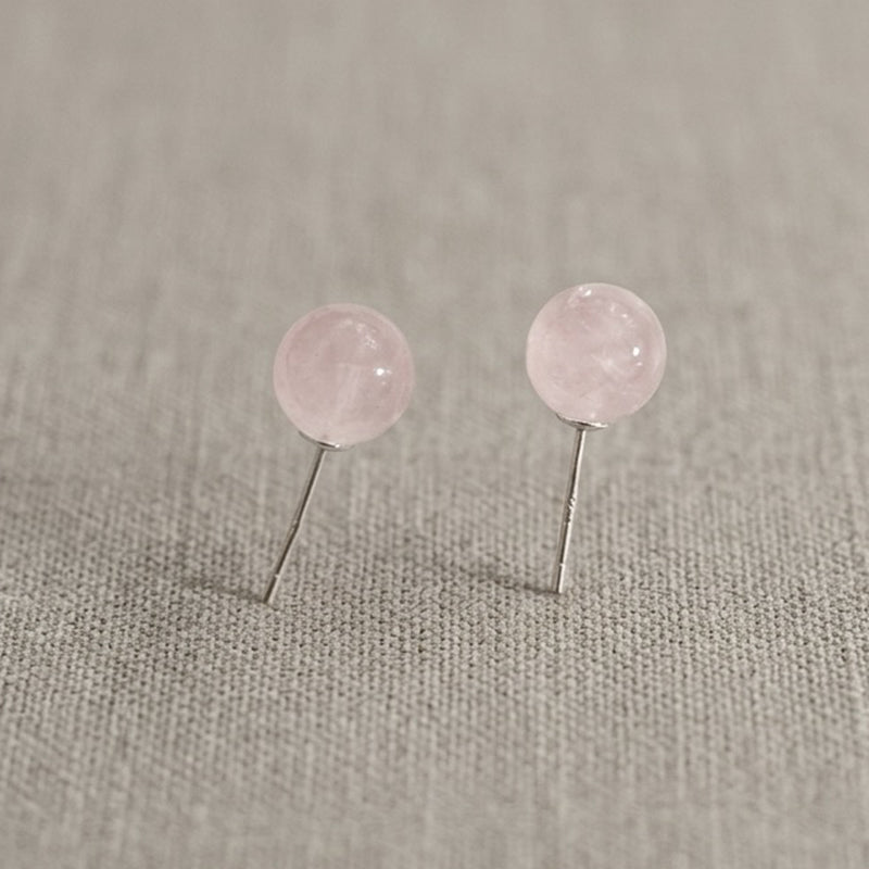 Pair of pink round earrings on a gray fabric background