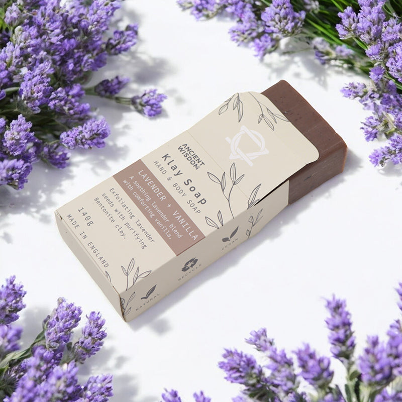 Bar of soap with a brown and beige label surrounded by lavender flowers on a white background