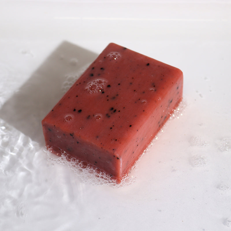 Red soap bar with black specks on a white background