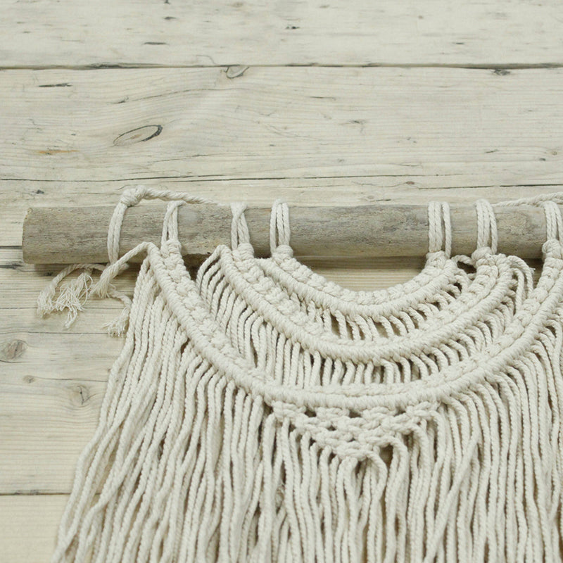 Macrame wall hanging with natural fibers on a wooden surface