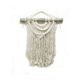 Macrame wall hanging with white strings on a wooden stick against a white background